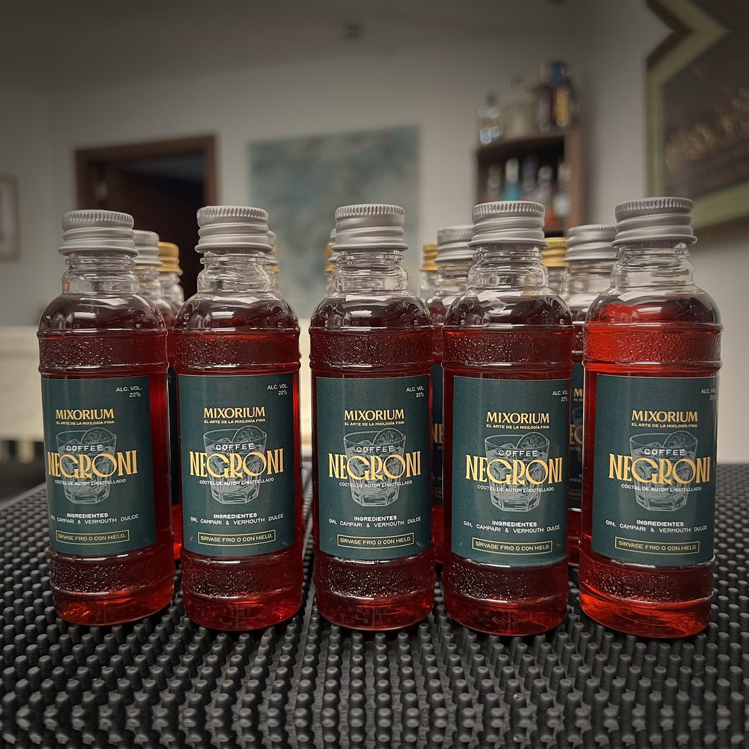 Cinco botellas individuales de 90 ml de Coffee Negroni, alineadas sobre la barra